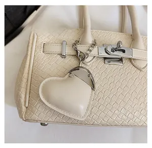Detail of cream leather heart-shaped bag charm with silver metal hardware and lobster clasp
