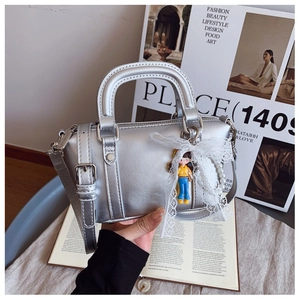 Detail of silver metallic Boston bag featuring lace bow and pearl chain accessories