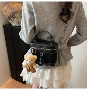 Détail du sac vanity en cuir noir avec bandoulière chaîne et breloque ours adorable