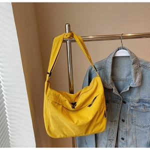Dettaglio di una borsa a tracolla gialla con cinturino regolabile e giacca di jeans