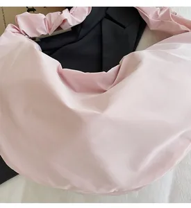 Detail of light pink nylon shoulder bag with shiny texture and scrunchie pleated strap