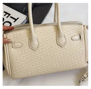 Detailed view of woven texture and premium buckle on a cream white Kelly style handbag
