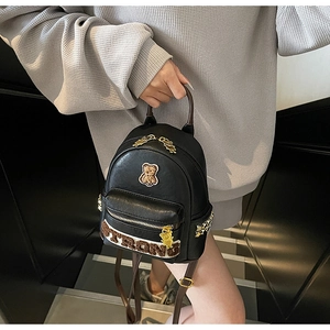 Détail du mini sac à dos noir avec écusson ourson et rivets métalliques latéraux