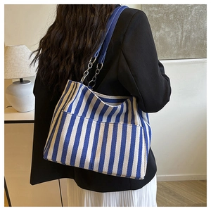 Détail du cabas en toile à rayures bleues et blanches avec bandoulière en cuir et chaîne