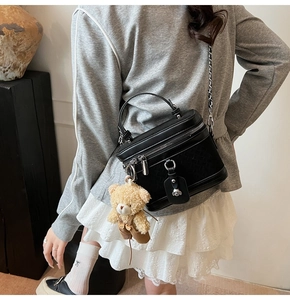 Détail d'un sac boîte noir tressé avec bandoulière chaîne et charmant ours en peluche