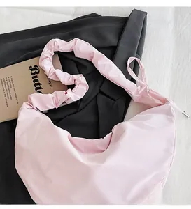 Close-up of pink pleated dumpling bag with ruffled adjustable shoulder strap details
