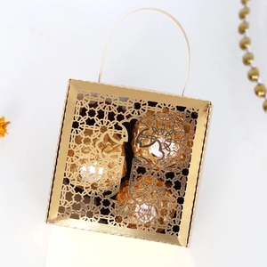 Detail of laser-cut hollow golden cross candy box with handle for wedding favors