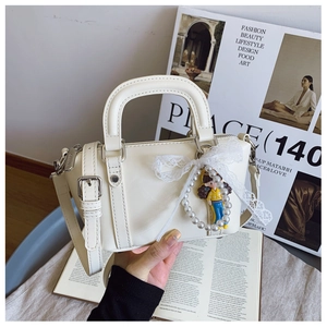 Detail of cream white leather handbag with lace bow, pearl charm and silver hardware