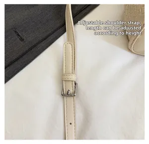 Detail of adjustable cream faux leather shoulder strap with polished silver buckle hardware
