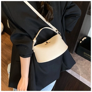 Detail der cremefarbenen Handtasche aus Leder mit goldener Schließe und verstellbarem Gurt