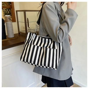 Détail du sac cabas en toile à rayures noires et blanches avec bandoulière chaîne