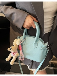 Bolso de mano azul claro de cuero granulado con un lindo colgante de perro de peluche