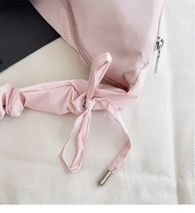 Detail of light pink pleated bag with adjustable drawstring and silver metal zipper