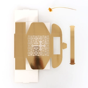 Flat lay of unassembled golden mirror paper gift box with laser-cut cross design
