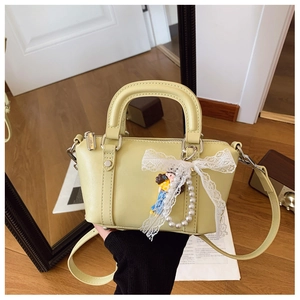 Detail of light green leather handbag with lace bow and elegant pearl charm accessories