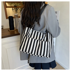 Détail du sac cabas rayé montrant la texture tissée, la bandoulière et la poche avant