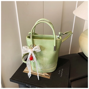 Détail du sac seau vert clair avec nœud en dentelle blanche et texture en similicuir