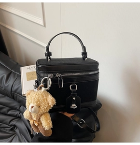Détail du sac bowling en similicuir noir avec rabat tressé et charm ours en peluche beige