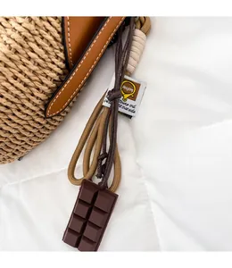 Detailed close-up of woven straw bag texture with leather trim and chocolate charm