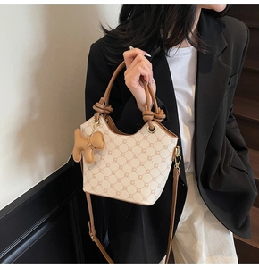 Détail du sac seau monogramme beige avec poignée en cuir marron et breloque chien