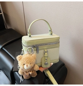 Détail du sac tressé vert pistache avec breloque d'ours en peluche et fermetures argentées