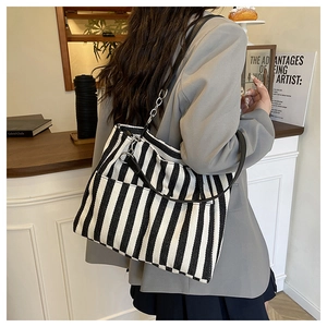 Détail du sac cabas en toile rayée avec bandoulière en cuir et chaîne métallique chic