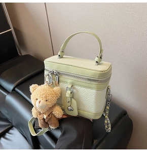 Détail du sac à main vert clair tressé avec breloque ourson et bandoulière chaîne