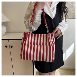 Détail du cabas en toile rayée rouge et blanc avec sangle cuir et chaîne argentée