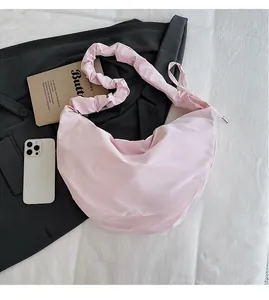 Detailed view of large pink nylon crossbody bag with ruffled shoulder strap and storage space