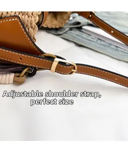 Detail of adjustable brown leather shoulder strap with golden buckle on straw bag