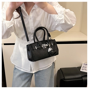 Close-up of black woven texture handbag featuring a silver lock and heart pendant detail
