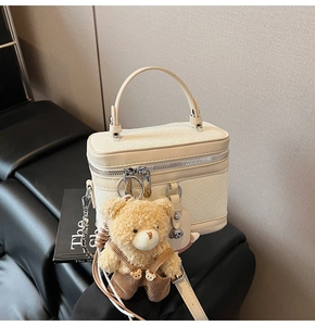 Détail de la trousse de toilette tressée crème avec chaîne argentée et charm ours en peluche