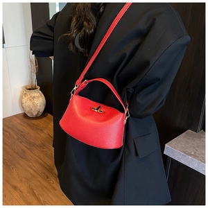 Rote Damenhandtasche aus genarbtem Leder mit goldenem Drehverschluss am Blazer