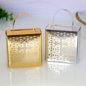 Detail of laser-cut cross patterns on gold and silver wedding favor gift boxes with handles