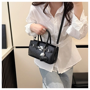 Side view of black woven texture Kelly bag with silver lock and heart charm detail