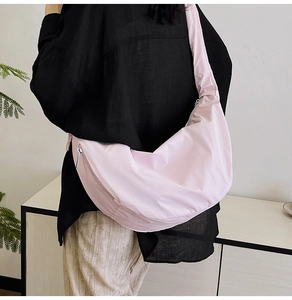 Pink crescent crossbody bag detail showing smooth pleated nylon texture and wide strap