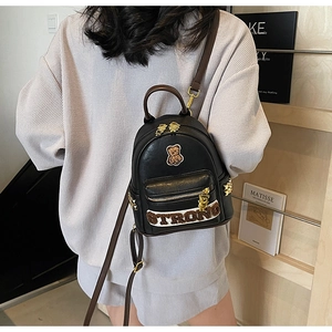 Détail de la broderie ours et des rivets étoile sur le sac à dos en cuir noir porté