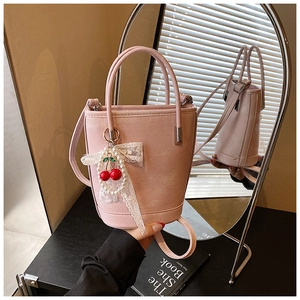 Sac seau rose avec breloques cerise en perles et nœud en dentelle sur support noir