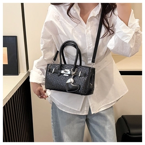 Close-up of black woven texture handbag with silver lock and heart charm detail