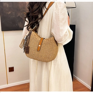 Detail of woven straw bucket bag with leather strap, silk scarf and chocolate charm