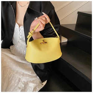Gelbe Handtasche mit Litschi-Struktur und Metalldrehverschluss am Model gezeigt
