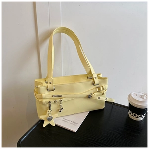 Détail du sac en cuir jaune crème avec boucles métalliques et pendentif en étoile
