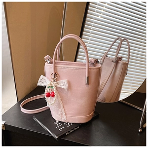 Détail du sac seau rose avec pendentif cerise en dentelle et similicuir texturé