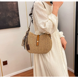 Close-up of woven straw tote bag with brown leather strap and chocolate charm detail
