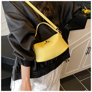 Detailansicht der gelben Handtasche aus Leder mit Narbenstruktur und Metalldrehverschluss