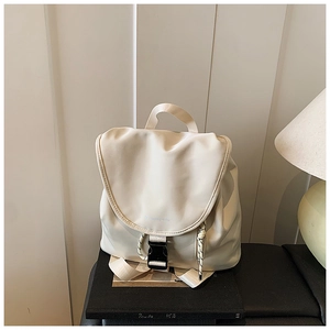 Dettaglio dello zaino crema con fibbia a patta e design minimalista con coulisse