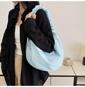 Close-up of light blue pleated hobo bag with cloud-style wrinkled shoulder strap detail