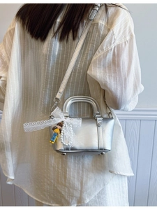Silver metallic Boston bag with pearls and lace bow charm shown on model