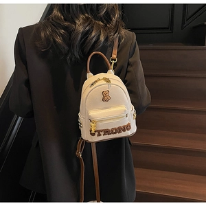 Détail du mini sac à dos en similicuir crème avec motif d'ours et bretelles marron porté