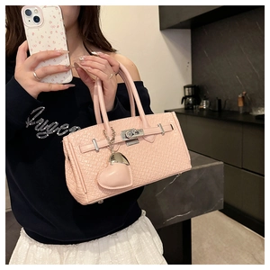 Detail of pink textured handbag featuring metal lock and heart pendant accessory